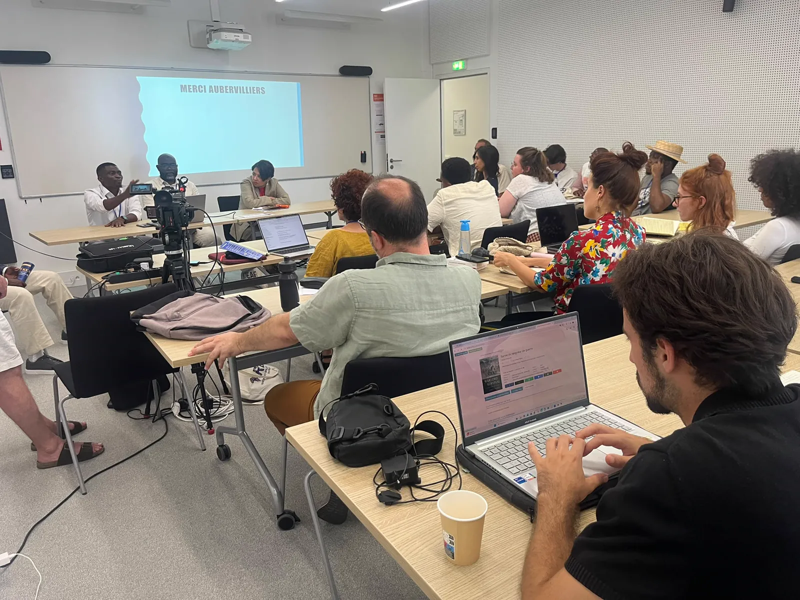 Atelier en cours : chercheurs autour des tables, ordinateurs et documents