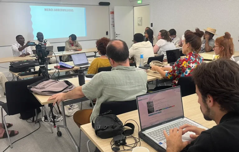 Atelier en cours : participants autour des tables face à l’écran
